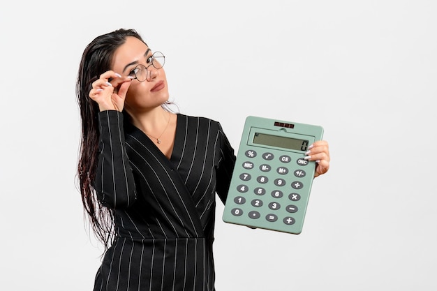 Vue De Face Jeune Femme En Costume Strict Sombre Tenant Une Grosse Calculatrice Sur Fond Blanc Beauté Femme Mode Entreprise Travail De Bureau