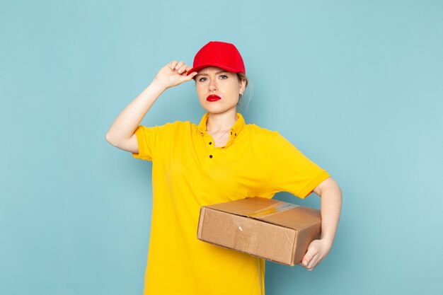 Vue de face jeune femme courrier en chemise jaune et cape rouge tenant le paquet sur le travail de l'espace bleu