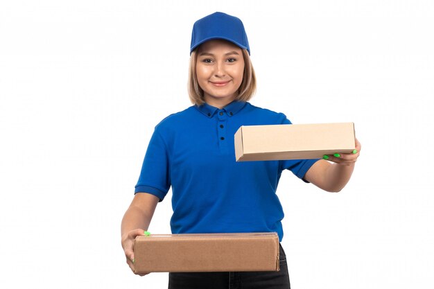 Une vue de face jeune femme courrier en uniforme bleu tenant des colis de livraison de nourriture