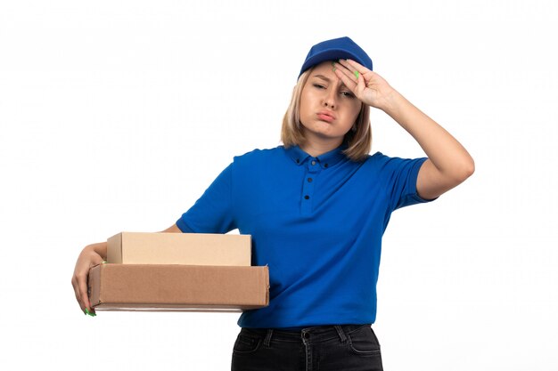 Une vue de face jeune femme courrier en uniforme bleu tenant des colis de livraison de nourriture