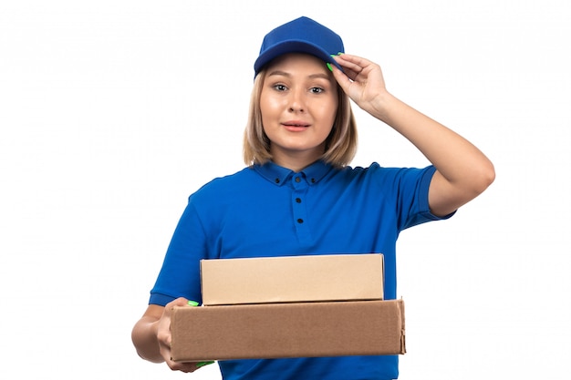 Une vue de face jeune femme courrier en uniforme bleu tenant des colis de livraison de nourriture