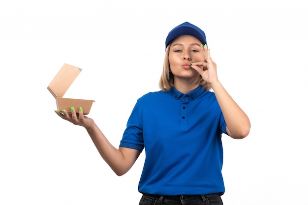 Une vue de face jeune femme courrier en uniforme bleu tenant le paquet de livraison de nourriture