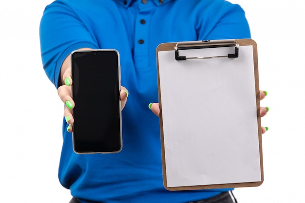 Une vue de face jeune femme courrier en uniforme bleu tenant le téléphone et le bloc-notes