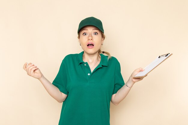 Vue de face jeune femme courrier en uniforme vert et cape verte écrivant des notes sur l'uniforme de femme espace lumière