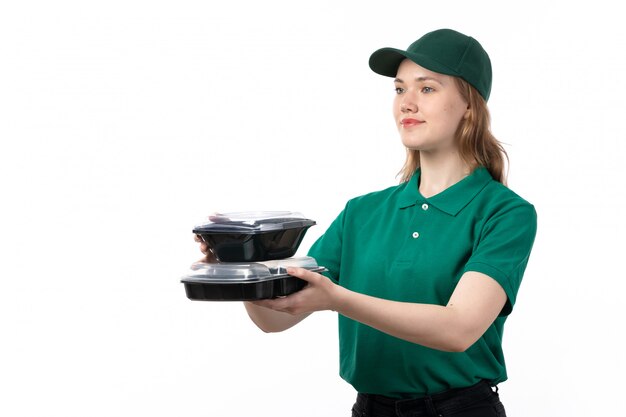 Une vue de face jeune femme courrier en uniforme vert offrant des bols de nourriture et souriant sur blanc