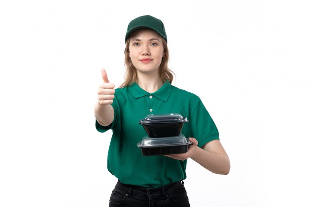 Une vue de face jeune femme courrier en uniforme vert tenant des bols avec de la nourriture souriant sur blanc