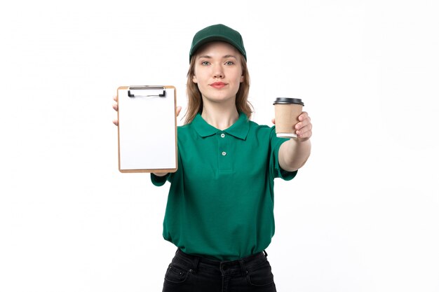 Une vue de face jeune femme courrier en uniforme vert tenant des tasses à café et bloc-notes sur blanc