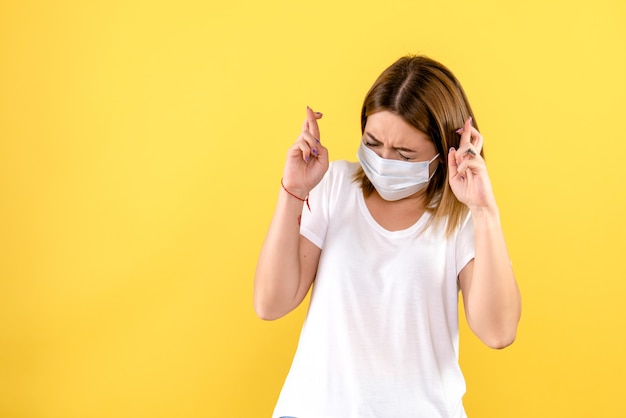 Vue de face de la jeune femme croisant ses doigts sur le mur jaune