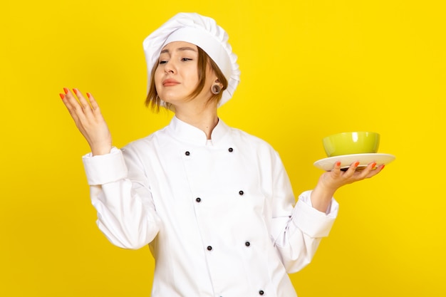 Une vue de face jeune femme cuisinier en costume de cuisinier blanc et bonnet blanc tenant des plaques vertes et rouges ravies sur le jaune