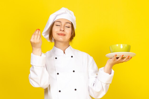 Une vue de face jeune femme cuisinier en costume de cuisinier blanc et bonnet blanc tenant des plaques vertes et rouges ravies sur le jaune