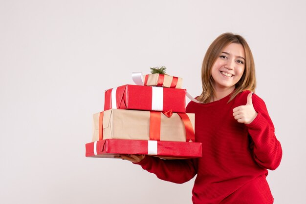 Vue de face jeune femme debout avec des cadeaux dans ses mains