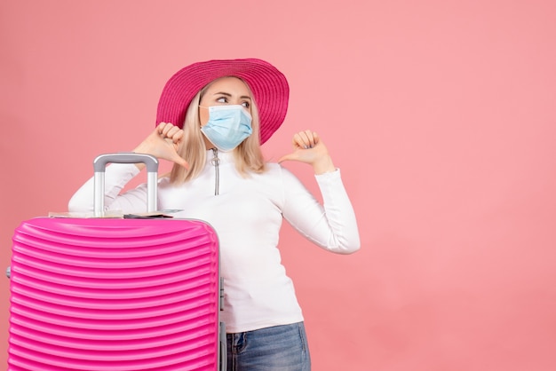 Vue de face jeune femme debout près de la valise pointant sur elle-même