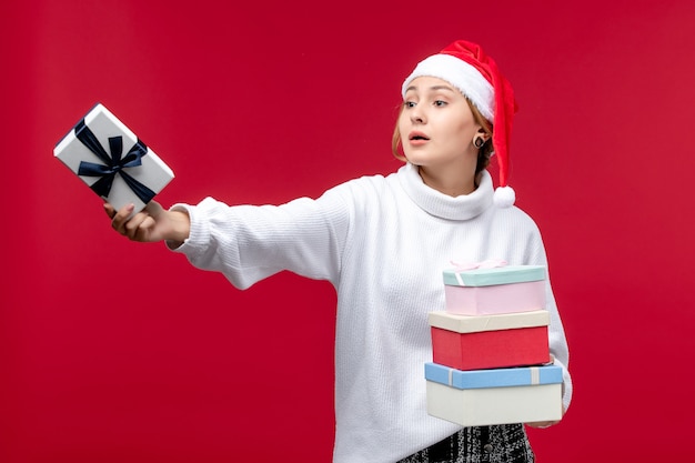 Vue de face jeune femme donnant des cadeaux de nouvel an sur fond rouge