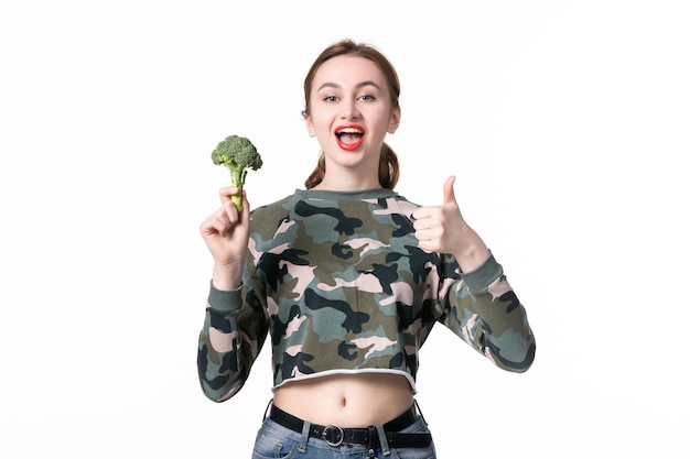 Vue de face jeune femme avec du brocoli vert sur blanc