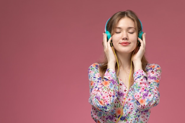 Vue de face jeune femme écoutant la chanson en silence sur un mur rose foncé