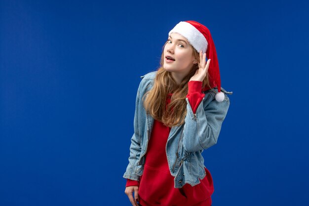 Vue de face jeune femme écoute sur fond bleu vacances Noël émotion