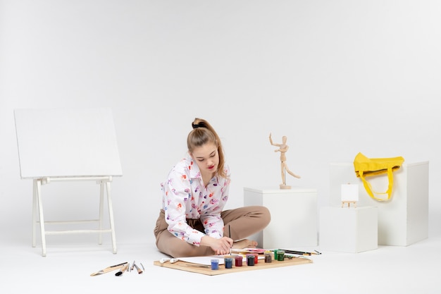 Vue de face jeune femme essayant de dessiner sur fond blanc