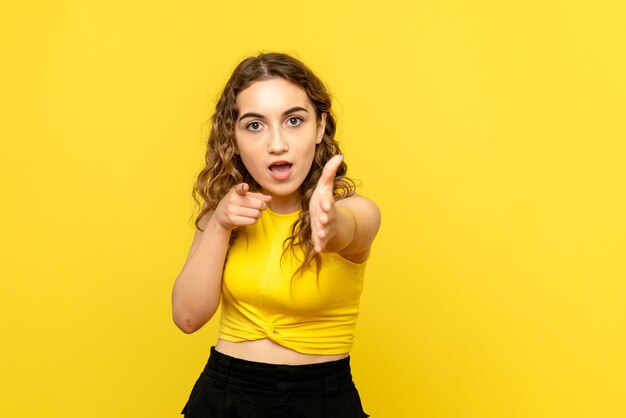 Vue de face de la jeune femme essayant de serrer la main sur le mur jaune