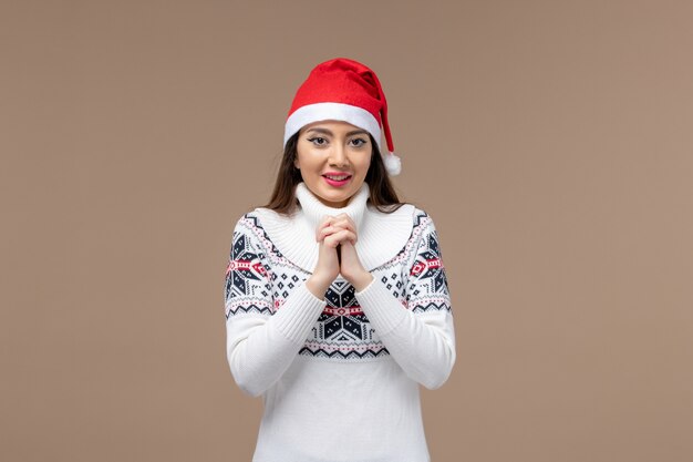 Vue de face jeune femme avec une expression souriante sur fond marron Noël nouvel an émotion