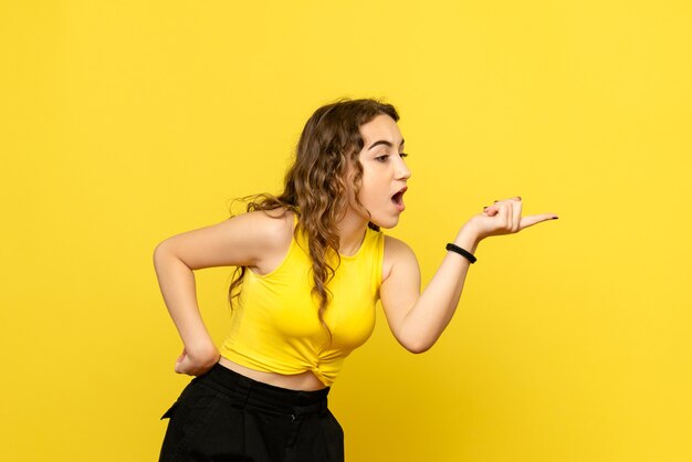 Vue de face de la jeune femme faisant valoir sur le mur jaune