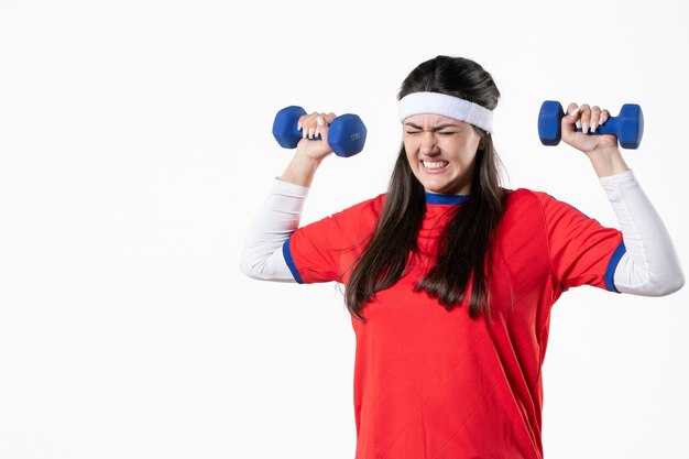 Vue de face jeune femme fatiguée dans des vêtements de sport avec des haltères bleus