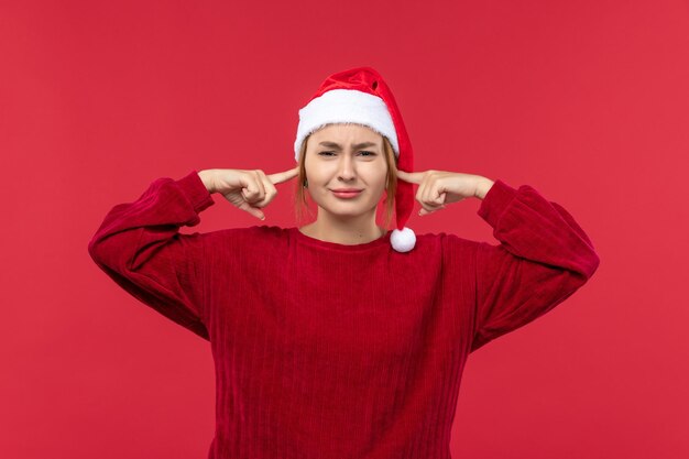 Photo gratuite vue de face jeune femme fermant ses oreilles, noël de vacances rouge