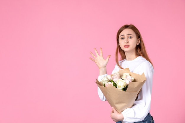 Vue de face jeune femme avec des fleurs comme jour de la femme présente sur fond rose horizontal féminin mars amour femme sensuelle égalité rose