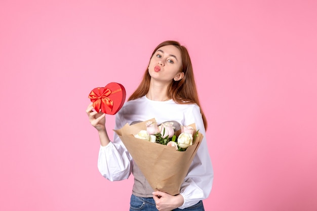 Vue de face jeune femme avec des fleurs et présente comme cadeau de jour de la femme sur fond rose horizontal mars égalité amour sensuel féminin date femme