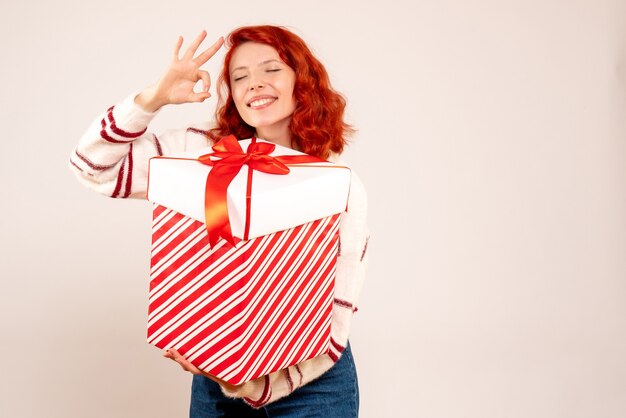 Vue de face de la jeune femme avec gros cadeau sur mur blanc