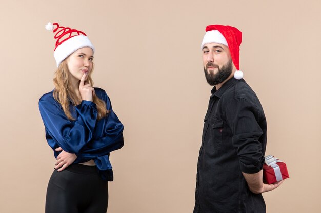 Vue de face de la jeune femme avec l'homme qui se prépare à lui donner un cadeau sur le mur rose