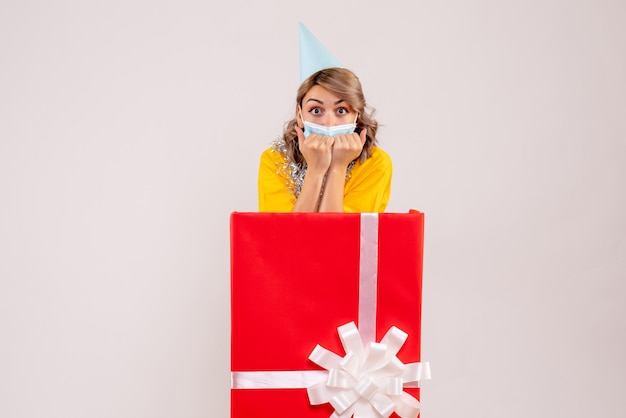 Vue de face jeune femme à l'intérieur de la boîte cadeau rouge en masque