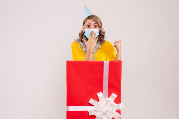 Vue de face jeune femme à l'intérieur de la boîte cadeau rouge en masque