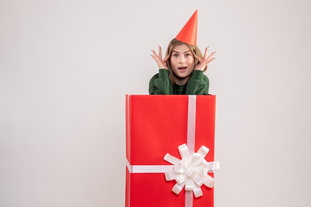 Vue de face jeune femme à l'intérieur de la boîte cadeau rouge