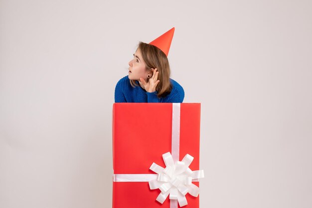 Vue de face jeune femme à l'intérieur de la boîte cadeau rouge