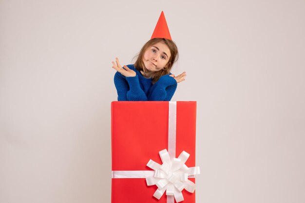 Vue de face jeune femme à l'intérieur de la boîte cadeau rouge