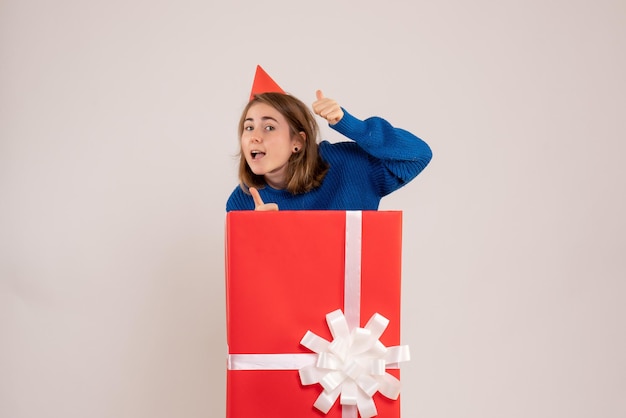 Vue de face jeune femme à l'intérieur de la boîte cadeau rouge