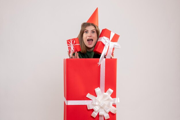 Vue de face jeune femme à l'intérieur de la boîte rouge avec des cadeaux