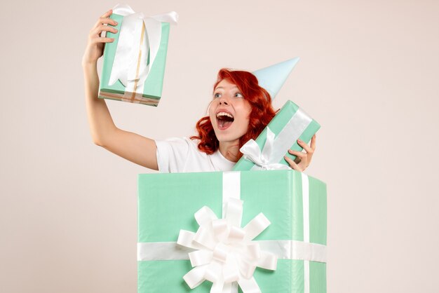 Vue de face jeune femme à l'intérieur présente tenant d'autres cadeaux sur fond blanc