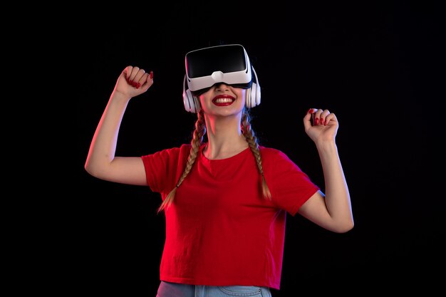 Vue de face d'une jeune femme jouant au vr dans un casque sur un jeu de technologie sombre d