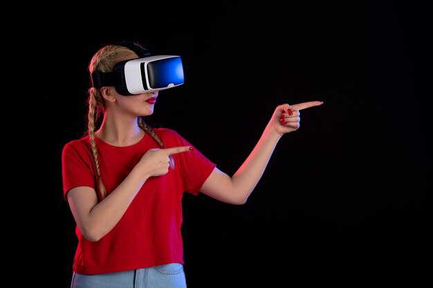 Vue de face d'une jeune femme jouant au vr sur un mur sombre