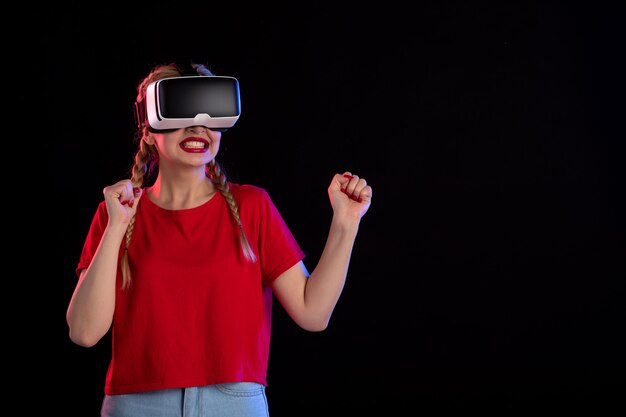 Vue de face d'une jeune femme jouant au vr sur un mur sombre