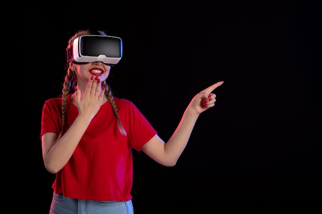 Vue de face d'une jeune femme jouant au vr sur un mur sombre