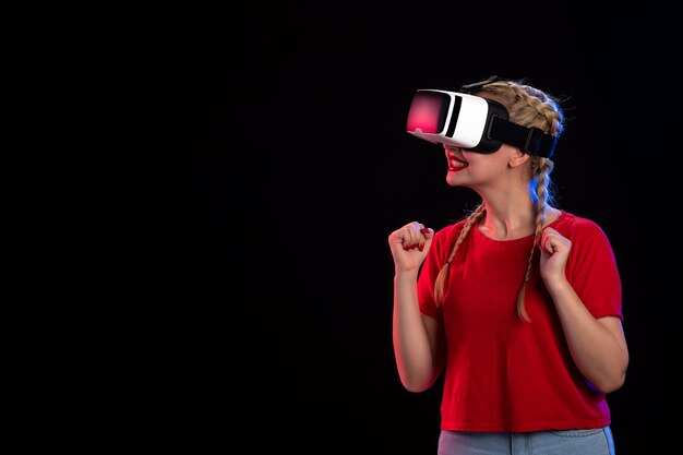Vue de face d'une jeune femme jouant à la réalité virtuelle sur le jeu visuel sombre.