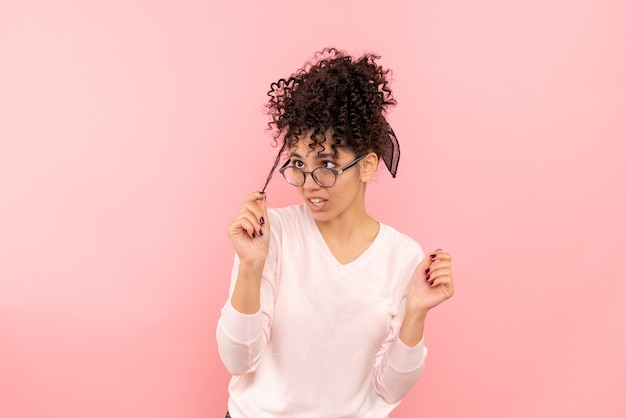 Photo gratuite vue de face de la jeune femme jouant avec ses cheveux sur un mur rose