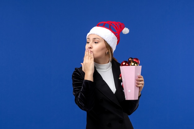 Vue de face jeune femme avec des jouets d'arbre sur le mur bleu couleur des émotions de vacances de nouvel an