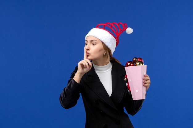 Vue de face jeune femme avec des jouets d'arbre sur le mur bleu couleur des émotions de vacances de nouvel an