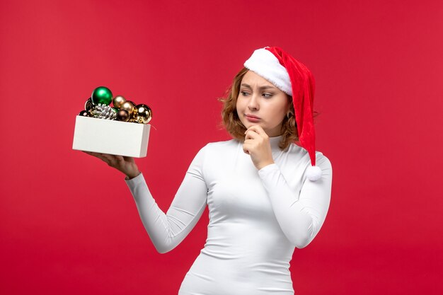 Vue de face de la jeune femme avec des jouets de Noël sur rouge