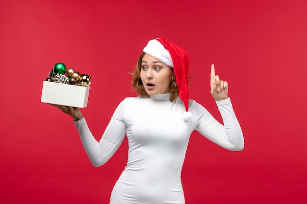 Photo gratuite vue de face de la jeune femme avec des jouets sur le rouge