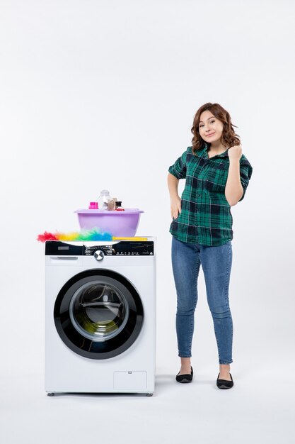 Vue de face de la jeune femme avec lave-linge sur mur blanc