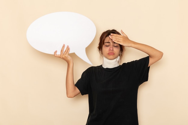 Vue de face jeune femme malade se sentir malade tenant un énorme panneau blanc sur une surface blanche